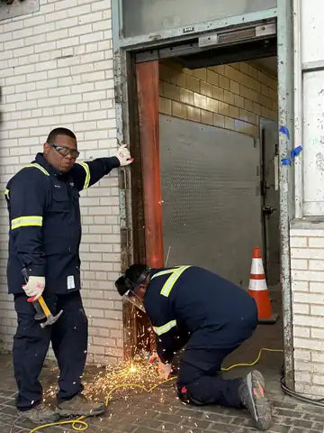 UFD installation crew cutting out an old steel door frame on a job site